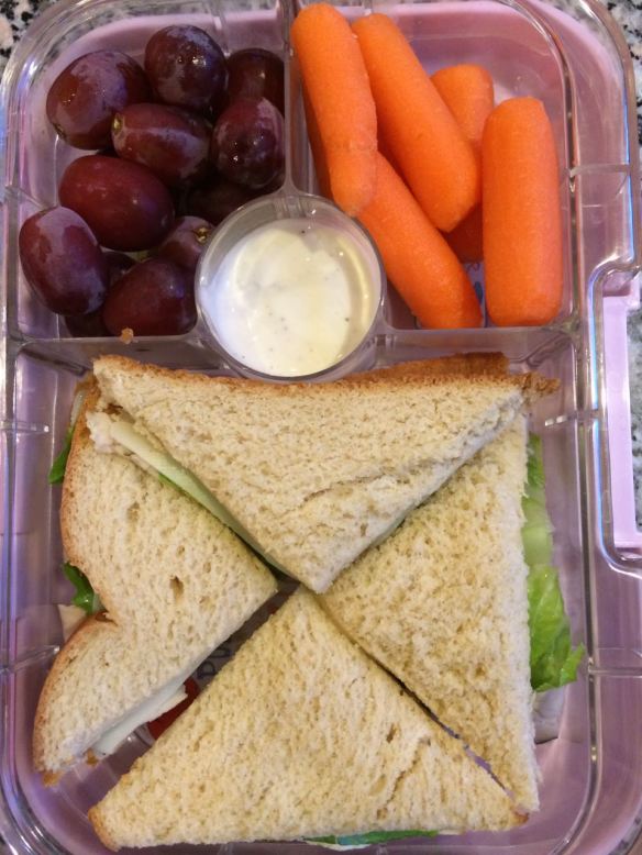 Turkey sandwich with grapes, carrots and ranch dip.